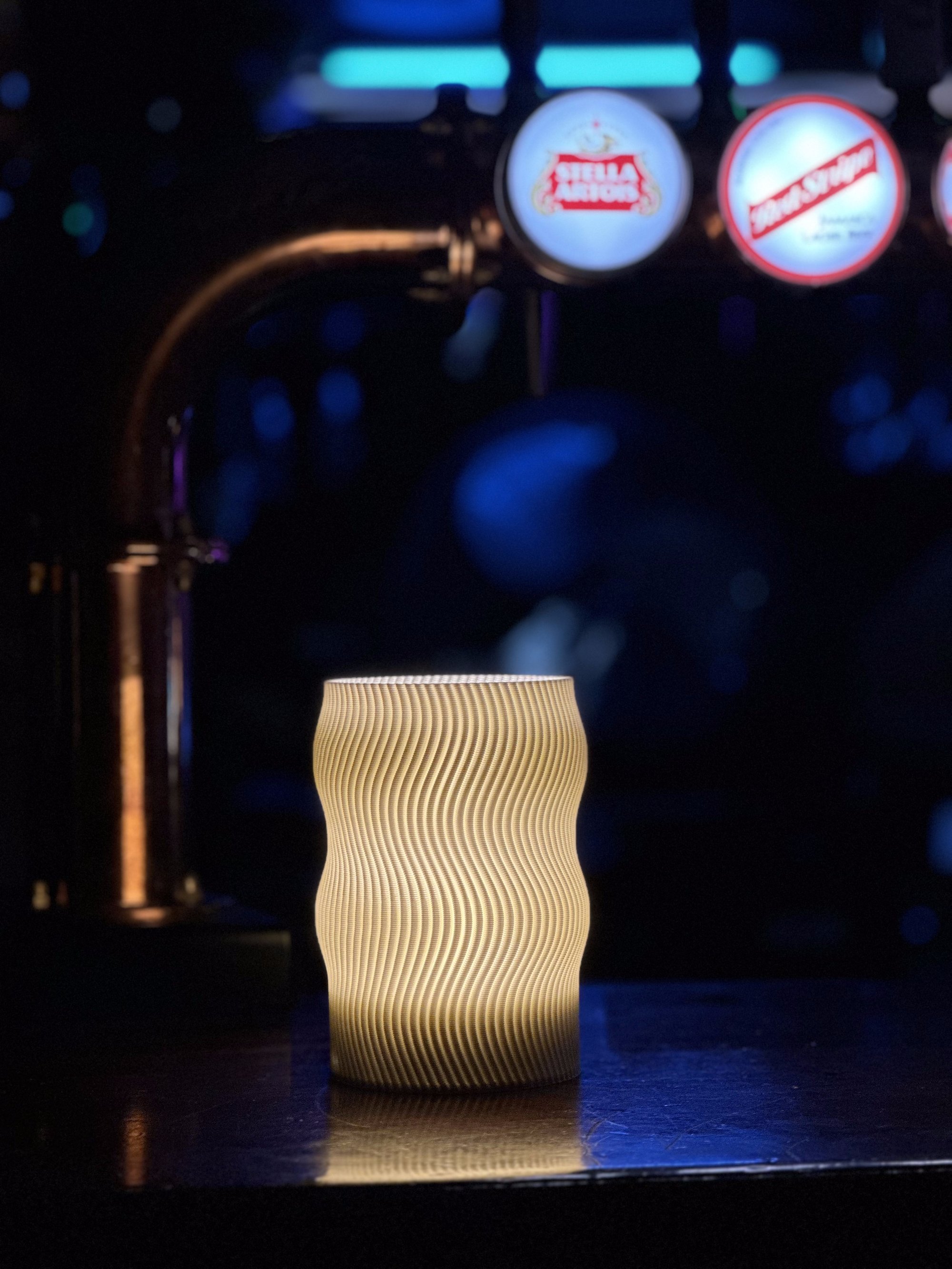 Flow Portable lamp glowing warmly on a pub bar counter, beer taps softly blurred behind it