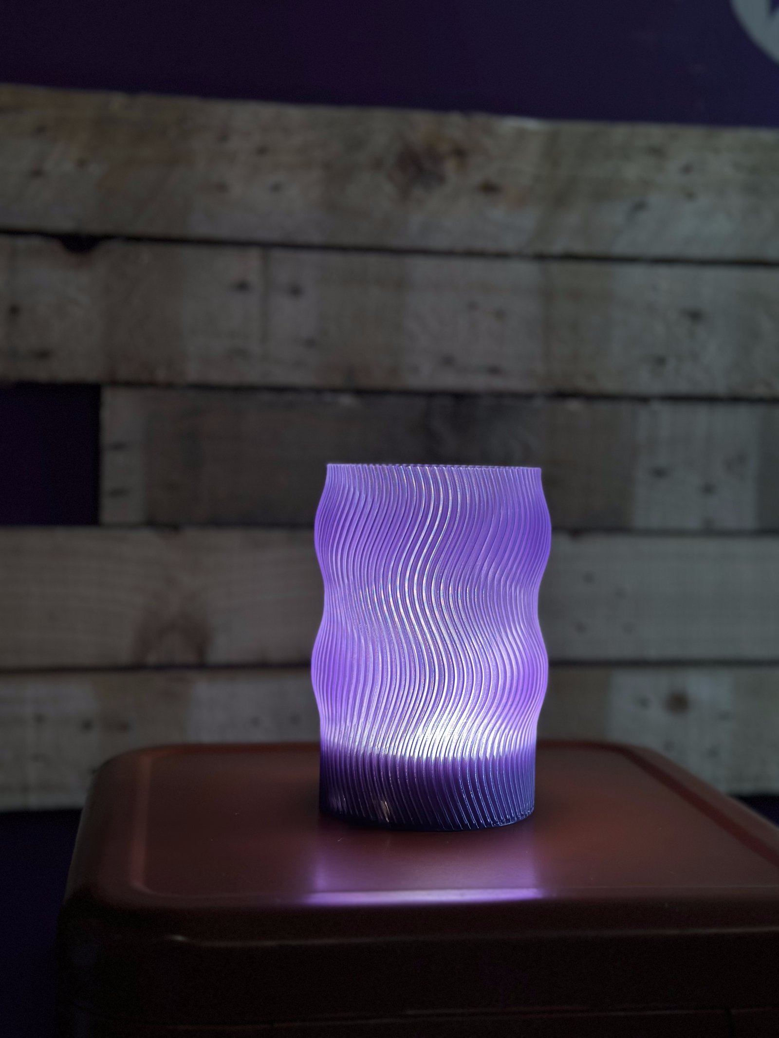 Flow lamp glowing purple against a reclaimed wood backdrop