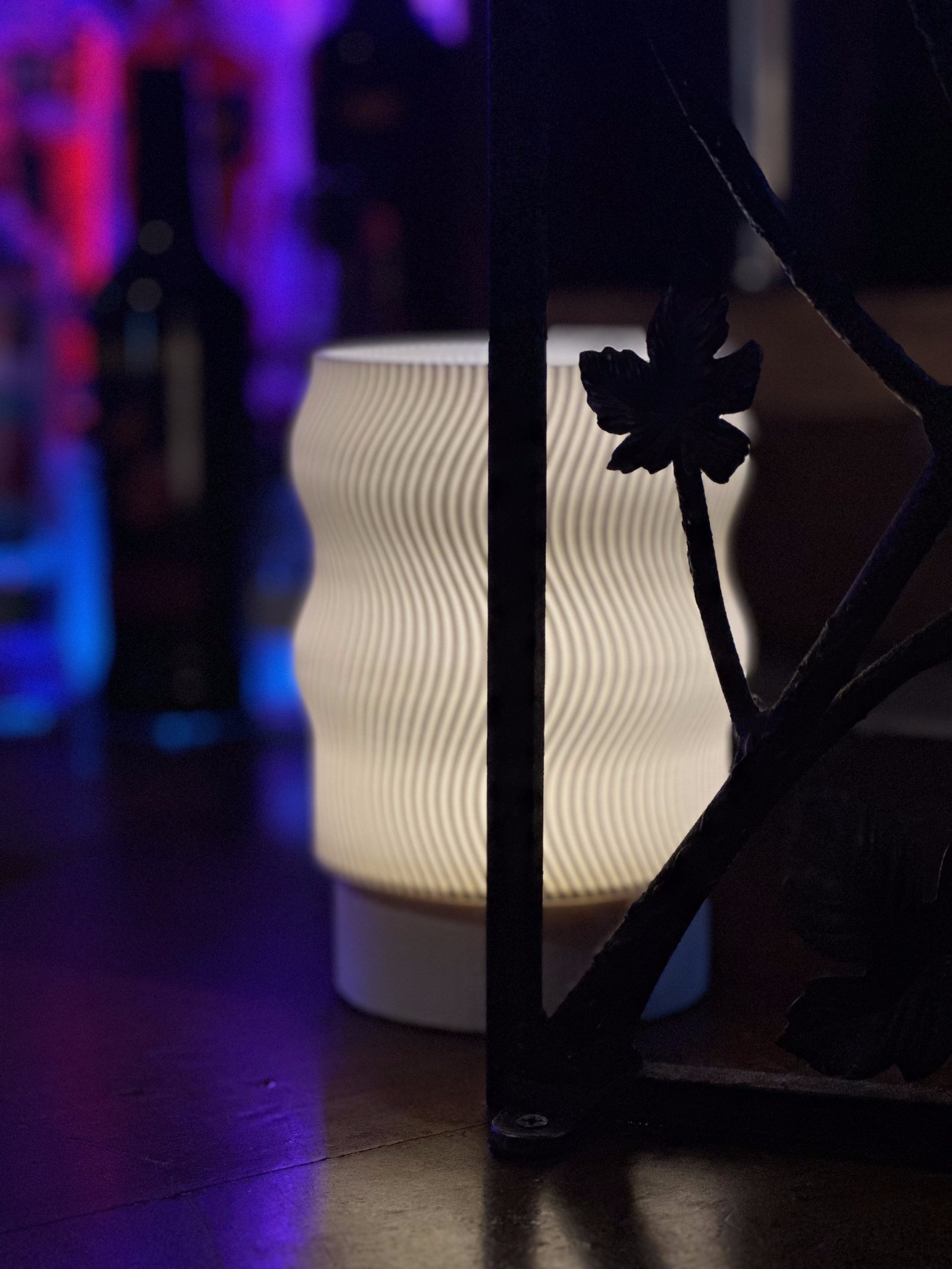 Flow Portable lamp glowing beside a wrought iron gate, studio shot